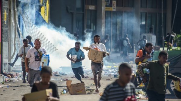 People run with merchandise as crowds leave shops with looted goods amid a state of unrest in Port Moresby