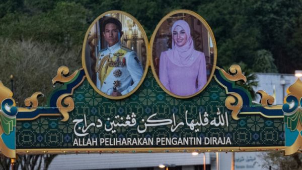 Portraits of Prince Abdul Mateen (L) and bride Yang Mulia Anisha Rosnah adorn a billboard over a road in Brunei ahead of their wedding