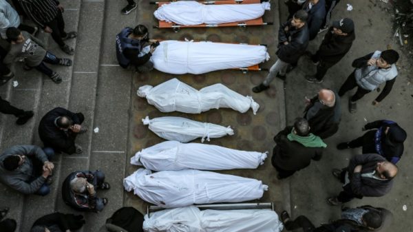 Mourners stand by shrouded bodies of people killed in strikes in the southern Gaza city of Khan Yunis on Tuesday