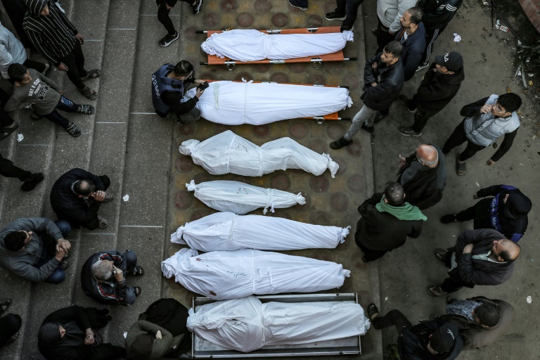 Mourners stand by shrouded bodies of people killed in strikes in the southern Gaza city of Khan Yunis on Tuesday