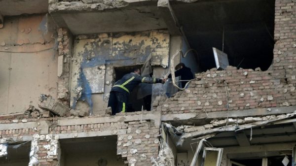 A rescuer evacuates a woman from a multi-storey residential building in Kyiv